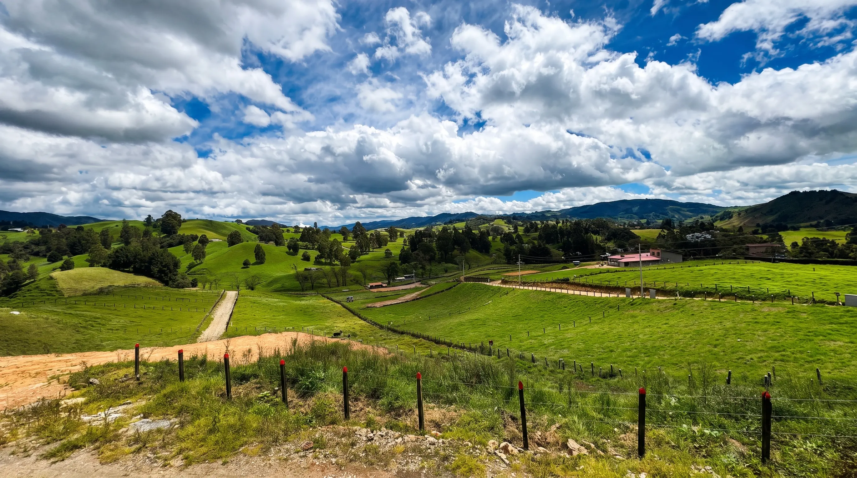 Panorámica de los lotes de Primavera Campestre con postes de cerramiento, prado verde y cordillera de fondo